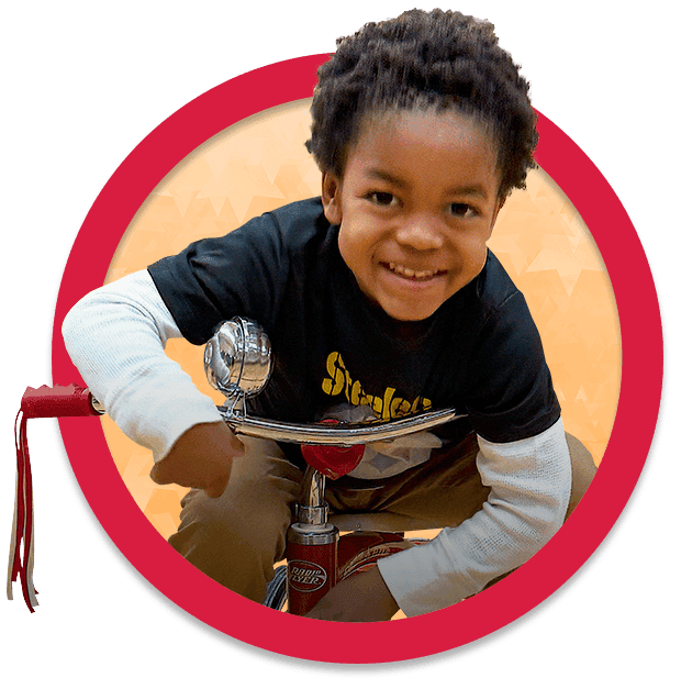 Smiling boy on tricycle.