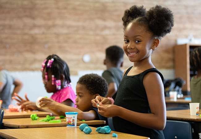 A female student works with blue play dough.