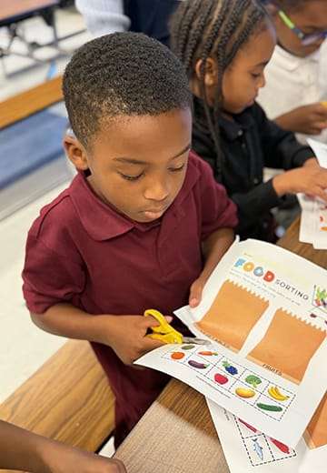 A boy cuts paper with scissors.